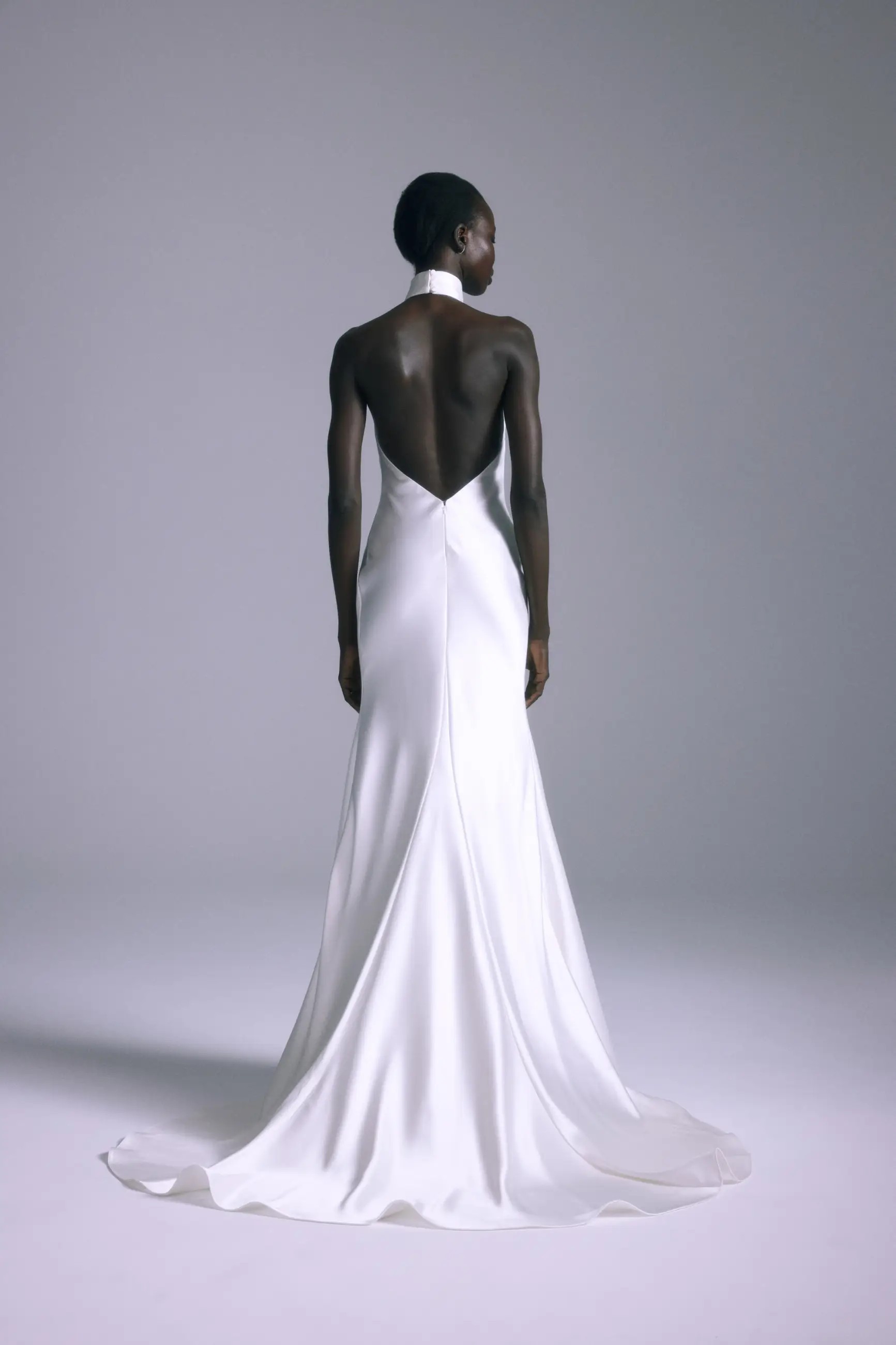 Model is wearing a minimalist silk halter bridal gown with a low back by amsale couture