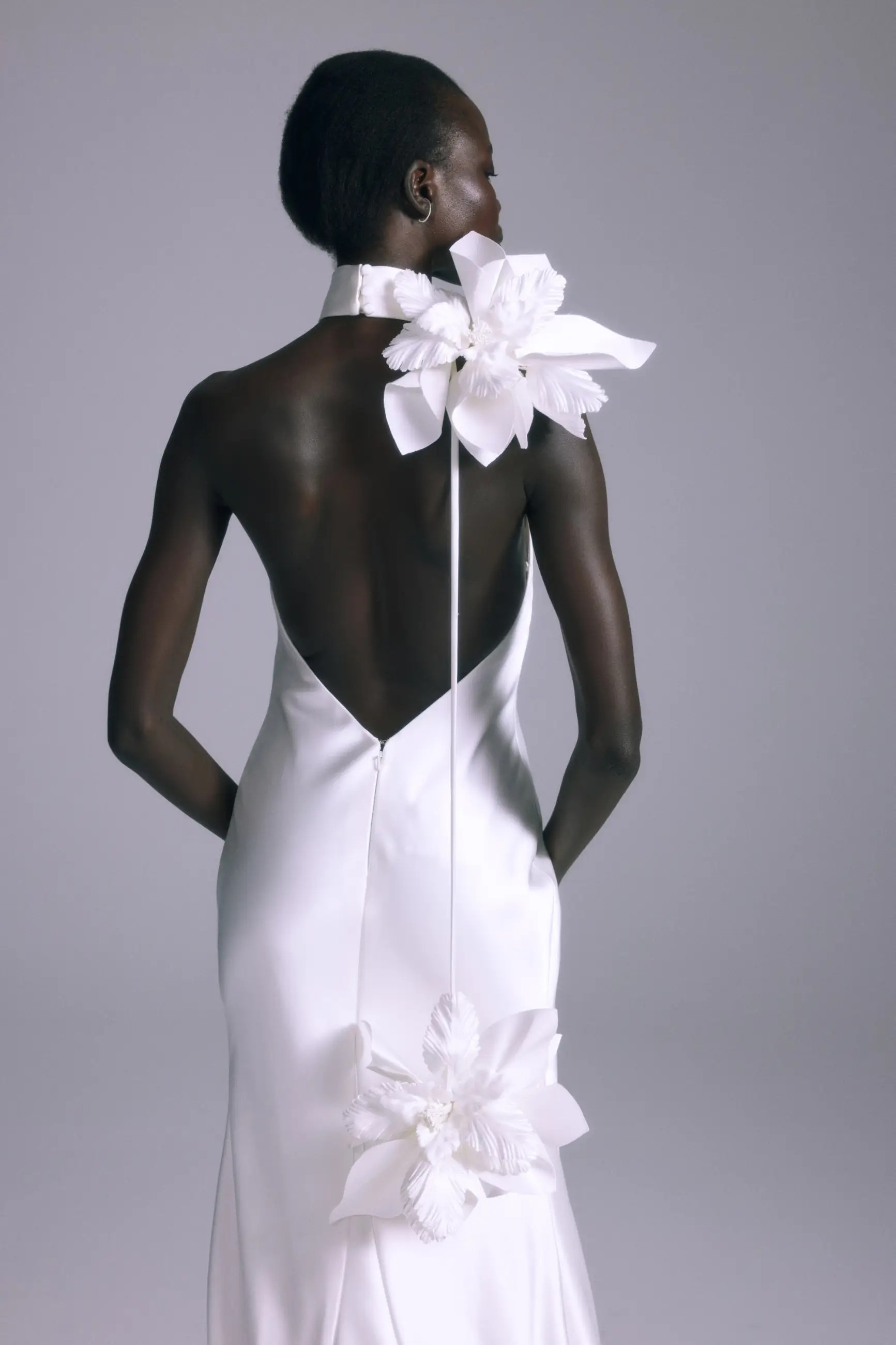 Model is wearing a minimalist silk halter bridal gown with a low back by amsale couture