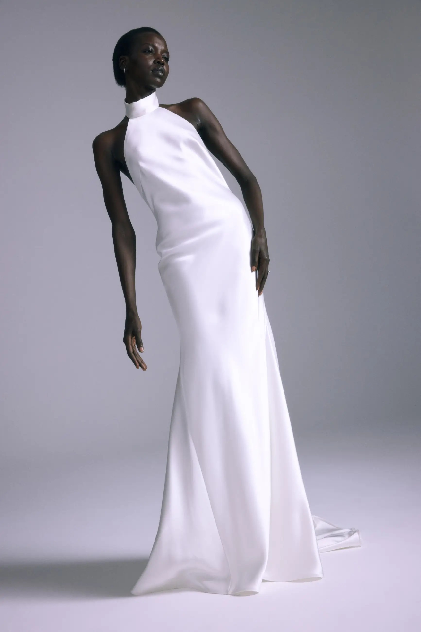 Model is wearing a minimalist silk halter bridal gown with a low back by amsale couture