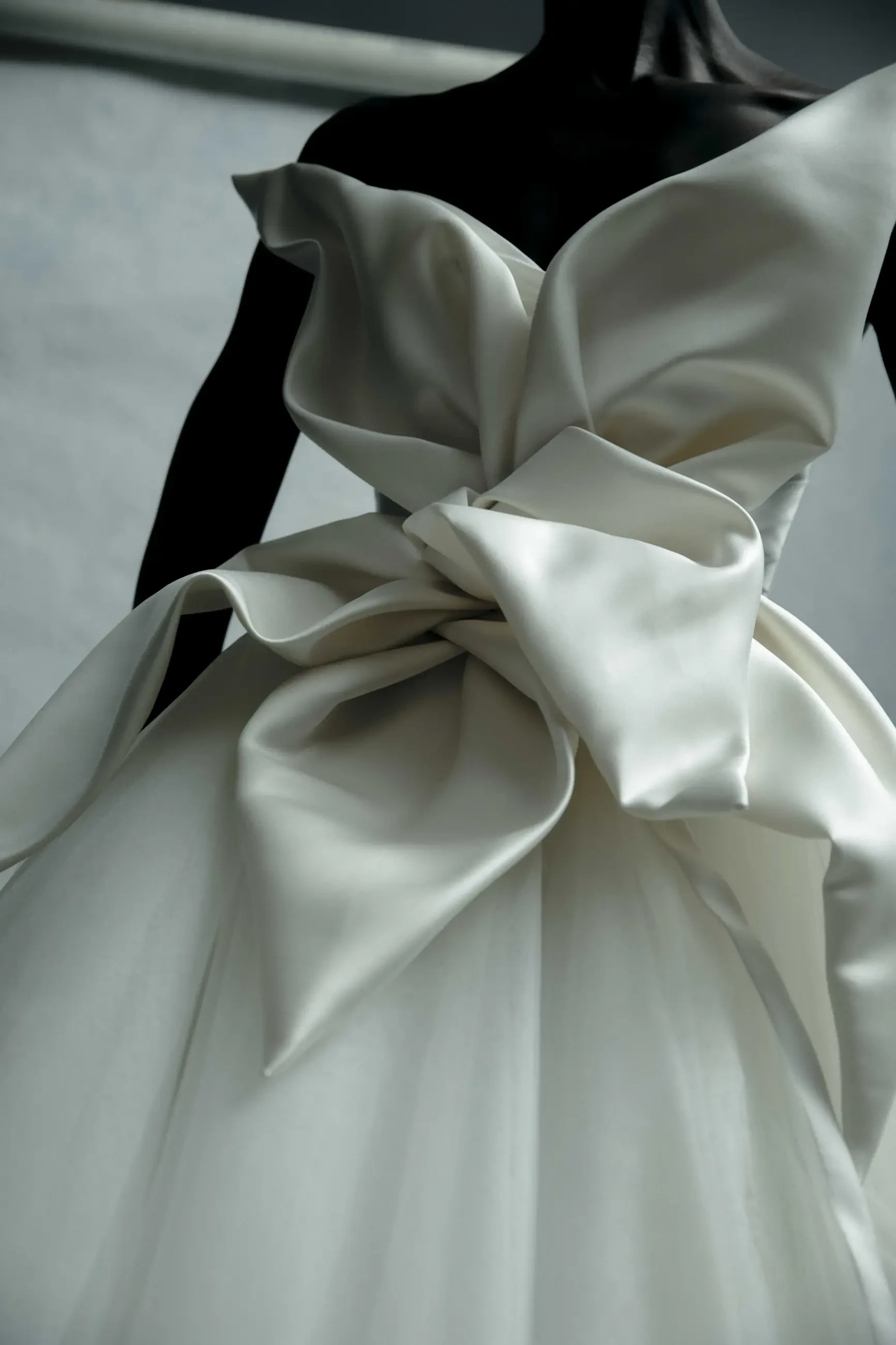 Model is wearing a taffeta and tulle ball gown with a ruched bodice and oversized 3D floral motif.