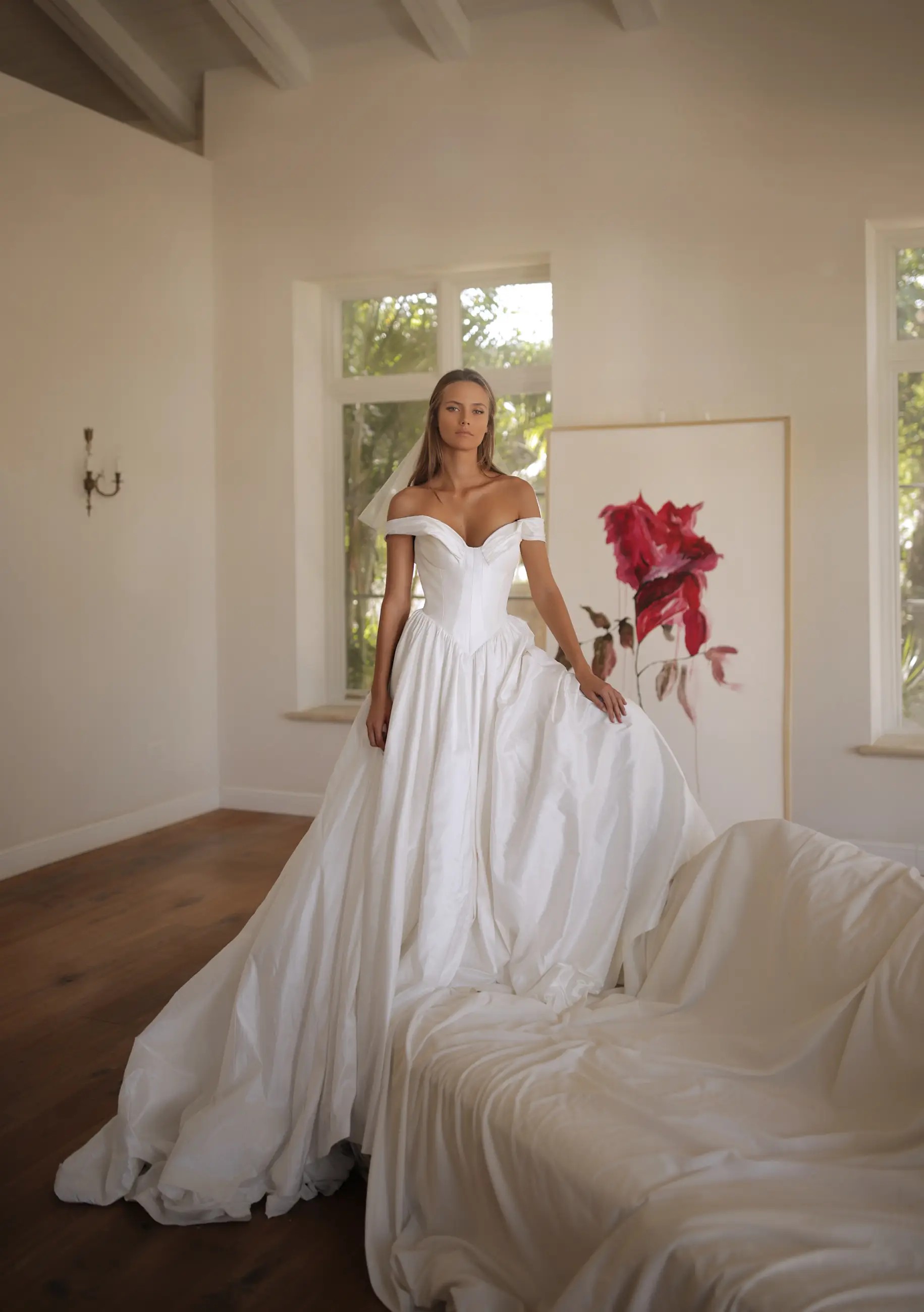 model is wearing an off the shoulder ball gown wedding dress with a basque waist