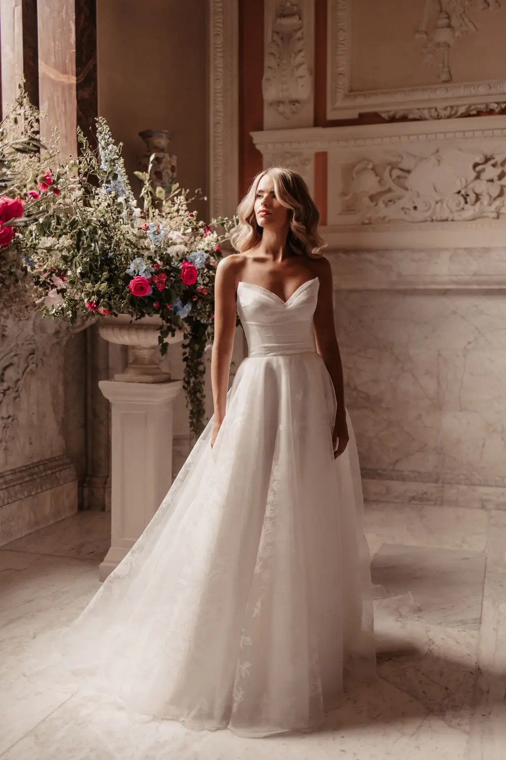 model is wearing an a-line wedding dress that's strapless with a pointed neckline