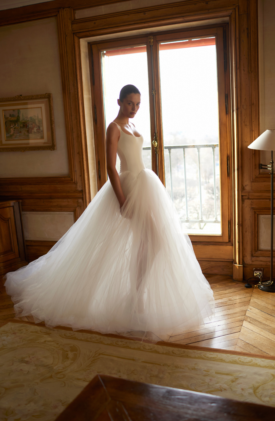 model is wearing a sleeveless wedding dress with a sheer tulle skirt