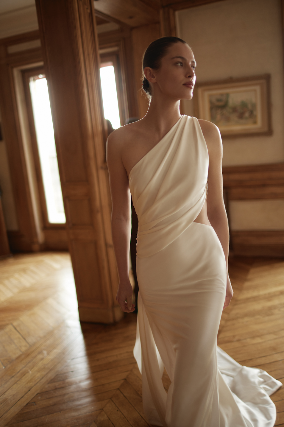 model is wearing a one shoulder asymmetrical neckline wedding dress by dana harel