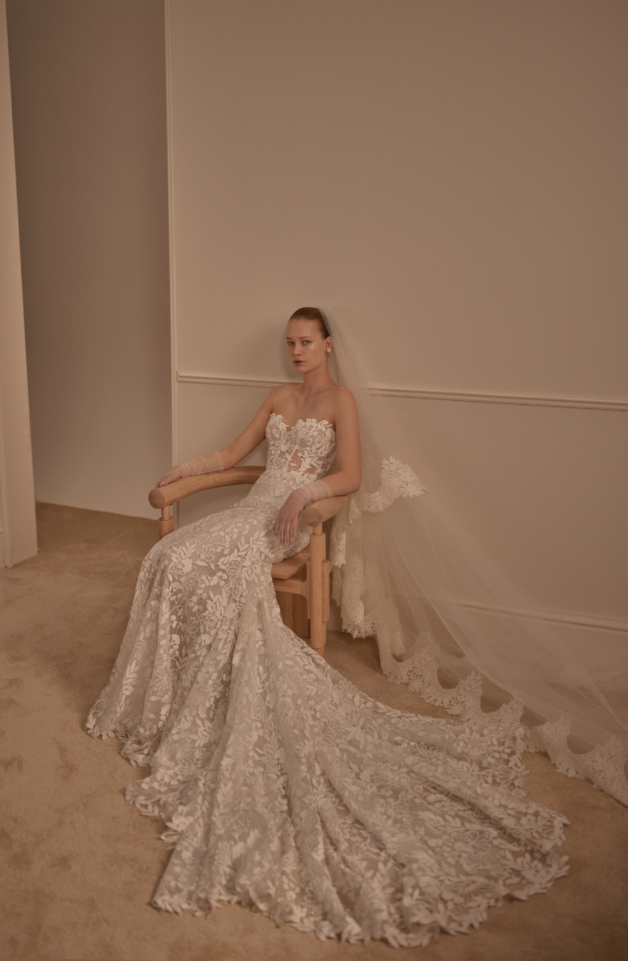 Model is wearing a lace fit and flare bridal gown with a sculpted silhouette and semi sheer bodice by lihi hod