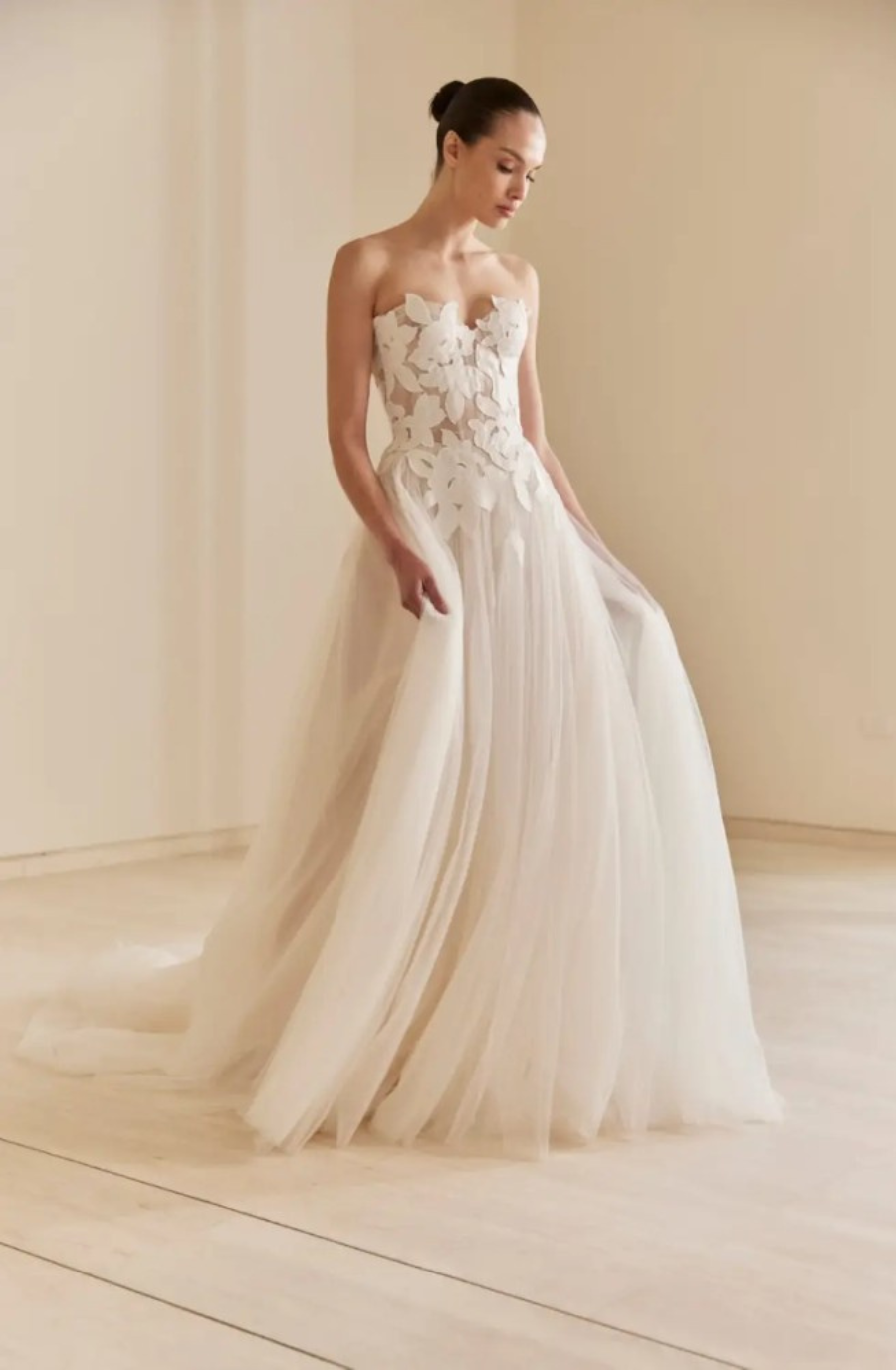 Model is wearing a strapless a-line bridal dress with a floral embroidered bodice and tulle skirt by mira zwillinger