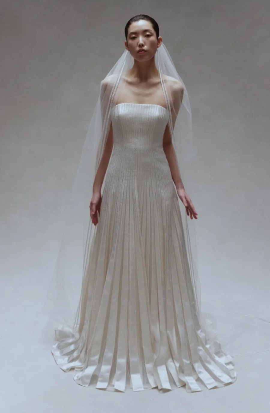 Model is wearing a strapless a-line wedding dress with a pleated skirt by amsale couture