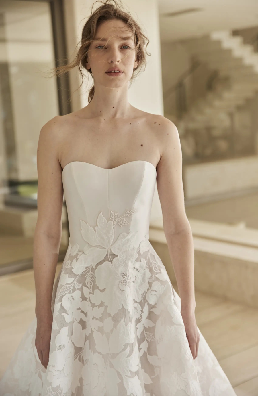 Model is wearing a strapless plain silk wedding dress with a corset and embroidered cotton floral full skirt by mira zwillinger