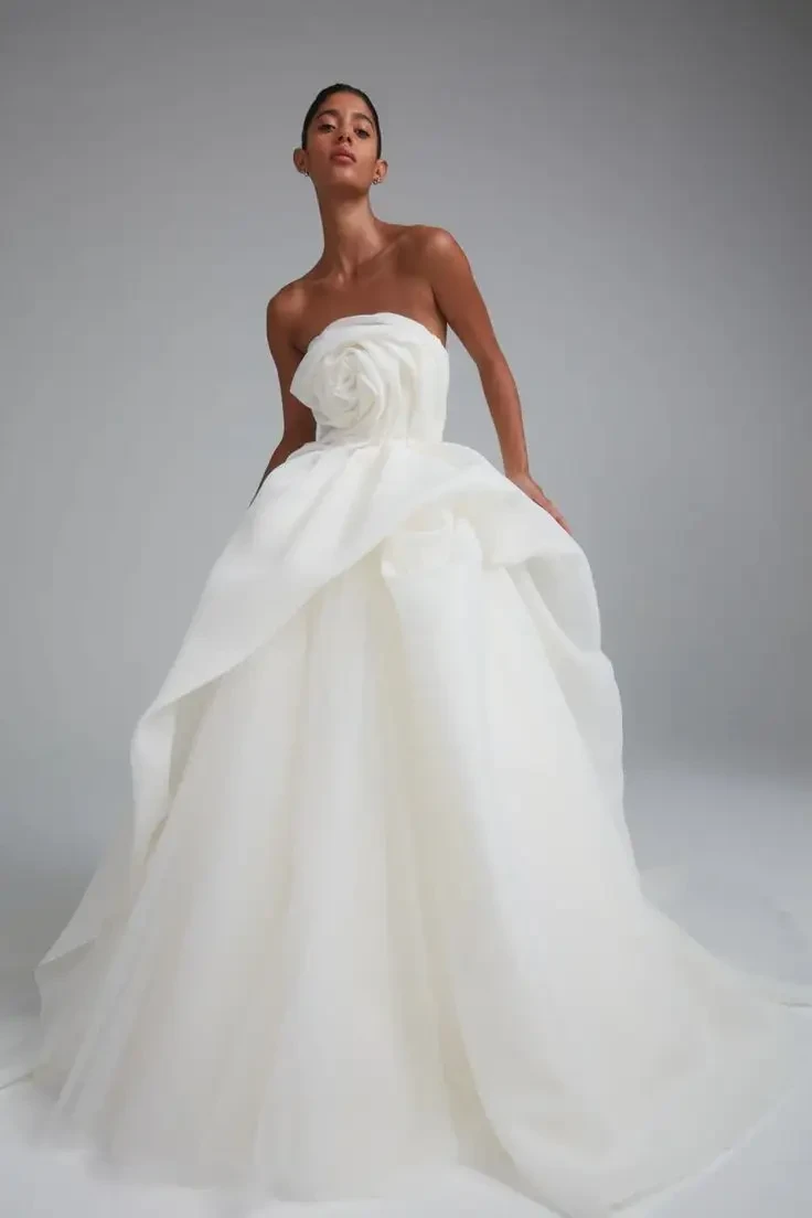 Model is wearing a hand-draped gazar ball gown with a flowing tulle skirt, each gown uniquely shaped for an organic silhouette.