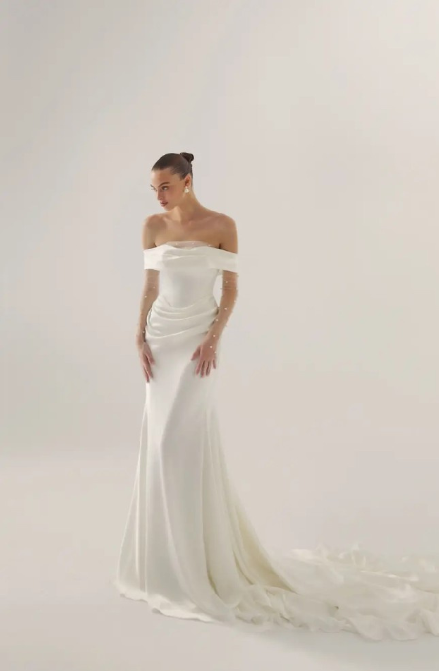 Model is wearing an off the shoulder fit and flare wedding dress with ruching by lihi hod