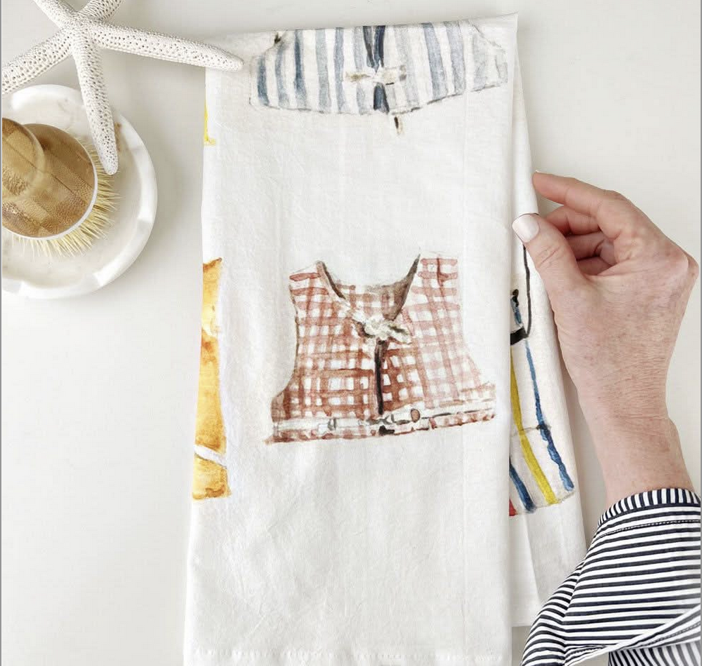 Image shows kitchen towels with printed nautical coat designs, neatly folded.